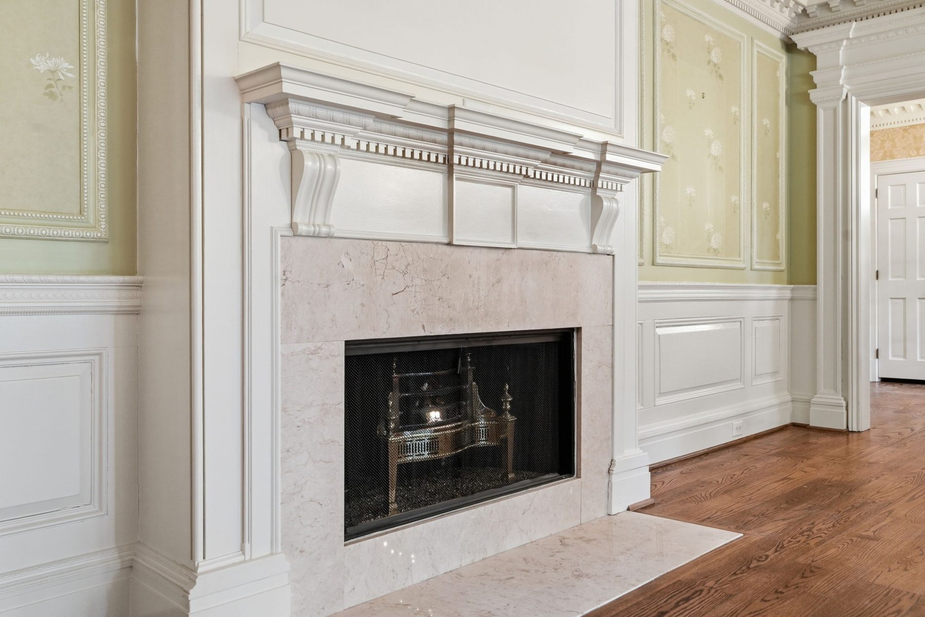 A marble fireplace against green damask walls